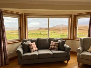 a living room with a couch in front of windows at Airigh nam Fiadh in Clachan