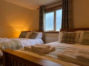 two beds in a room with a window at Airigh nam Fiadh in Clachan