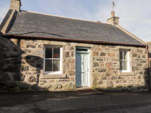 a stone house with a blue door and two windows at 2 Seafield Place in Portsoy
