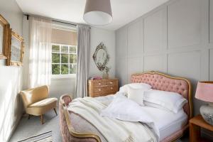 a bedroom with a bed and a chair and a window at Cotswold House in Moreton in Marsh