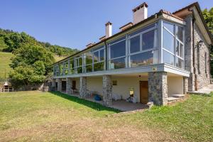 ein großes Haus mit großen Fenstern auf einem Hügel in der Unterkunft La Casona de Alesga, Asturias-Fresnedo in Fresnedo