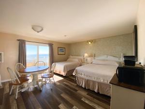 ein Hotelzimmer mit zwei Betten und einem Tisch in der Unterkunft Seashell Motel in Dennis