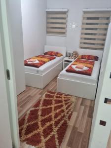 two beds in a small room with a rug at Apartman Meka in Sarajevo