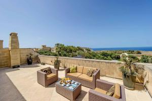 un patio con divani, tavolo e vista sull'oceano di The Olives Holiday Home a San Lawrenz