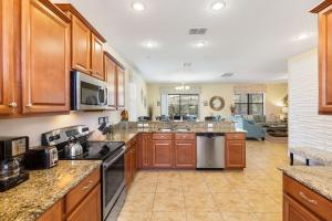 a large kitchen with wooden cabinets and a living room at Moonlight Ridge - 5 bed ChampionsGate Resort pool home in Davenport