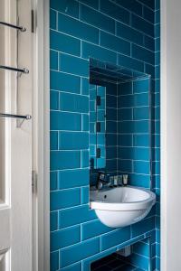 One Bedroom Apartment in Marylebone في لندن: حمام من البلاط الأزرق مع حوض ومرآة