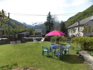 - une table et des chaises avec un parasol rose dans la cour dans l'établissement Gîte Lilubelle, à Ustou