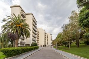 uma rua em frente a um edifício com uma palmeira em Apartamento Junto Playa Sardinero Con Parking em Santander