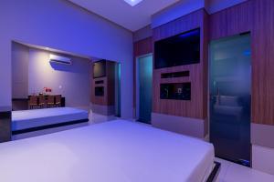a bedroom with a white bed and a tv at Sfera Motel in Manaus