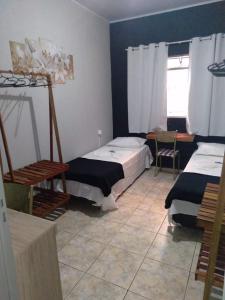 a bedroom with two beds and a table and a window at Pousada uberaba in Uberaba