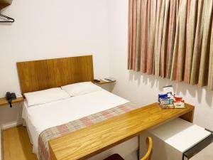 - une chambre avec un lit doté d'une tête de lit en bois dans l'établissement Hotel Rojas All Suite, à São Paulo