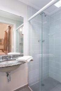 uma casa de banho com uma cabina de duche em vidro e um lavatório. em Hotel Rojas All Suite em São Paulo