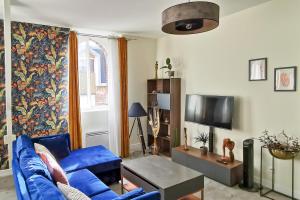 een woonkamer met een blauwe bank en een tv bij Les Appartements de la Nef d'Or in Saint-Quentin