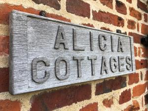 a sign on the side of a brick wall at Alicias Cottage, Bacton in Norwich