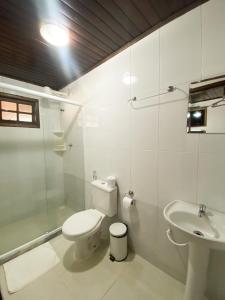 a white bathroom with a toilet and a sink at Pousada Bugio in Abraão