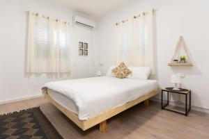 a white bedroom with a large bed and white curtains at אירוח פינת חן - מתחם אירוח מושלם עם בריכה משותפת in Ramot Naftali +30 photos