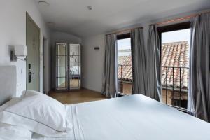 a bedroom with a white bed and a balcony at Posada Sillería - Historic boutique Hotel in Toledo