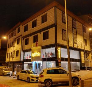 twee auto's geparkeerd voor een gebouw 's nachts bij BEYAZ İNCİ OTEL in Sivas