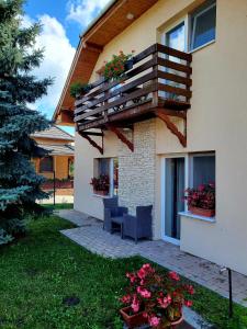 a house with two chairs and a balcony with flowers at Olivér Apartmanház in Balatonlelle
