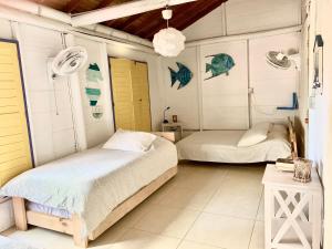 2 camas en una habitación con paredes blancas y puertas amarillas en Casita Caribe en reserva natural, playa privada, kayaks, wifi, aire acondicionado, en San Onofre