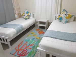 a room with two beds and a rug at No 12 Tugela Mouth in Tugela Mouth