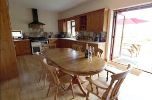 eine Küche mit einem Holztisch und Stühlen sowie eine Küche mit einem Fenster in der Unterkunft The Granary in Barnstaple