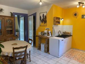 una cocina con paredes amarillas, una mesa, una mesa y un mantel en La petite marmite du lac de Vouglans, en Pont-de-Poitte