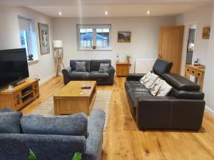 a living room with couches and a tv at Loch Ness House Blairbeg in Drumnadrochit