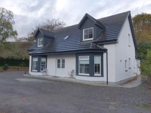 a white house with a black roof at Loch Ness House Blairbeg in Drumnadrochit