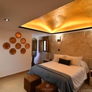 Hotel Boutique Casa Laja في سان ميغيل دي الليندي: غرفة نوم بسرير كبير وجدار حجري