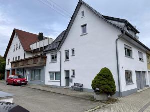 a white house with a red car parked in front of it at Schwabennestle - Ferienwohnung Albstadt-Onstmettingen in Albstadt