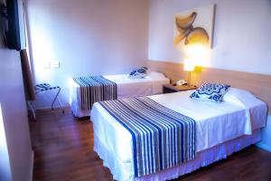 Una habitación de hotel con dos camas y una lámpara. en Hotel Nacional Inn Porto Alegre - Próximo ao Complexo Hospitalar Santa Casa e UFRGS, en Porto Alegre 37 fotos más