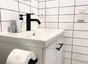 a white bathroom with a sink and a roll of toilet paper at Top-Apartment mit Parkplatz und Balkon in Reutlingen +7 photos