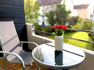 eine Vase mit roten Blumen auf dem Tisch auf dem Balkon in der Unterkunft Top-Apartment mit Parkplatz und Balkon in Reutlingen
