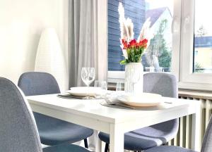 uma mesa branca com cadeiras e um vaso com flores em Top-Apartment mit Parkplatz und Balkon em Reutlingen