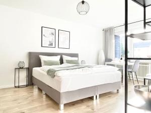 a white bedroom with a bed and a table at Top-Apartment mit Parkplatz und Balkon in Reutlingen
