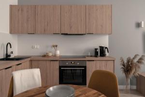 a kitchen with wooden cabinets and a table with chairs at HARBOR APARTMENTS - Sobieskiego in Katowice