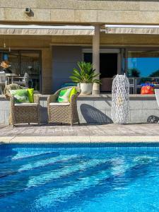 Una piscina con sillas de mimbre al lado de una casa. en Villa Montalvo, en Sanxenxo