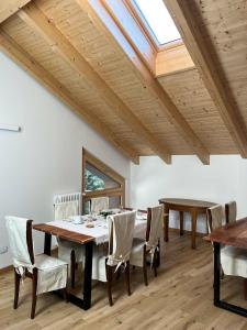 ein Esszimmer mit Holztischen und -stühlen und einem Dachfenster in der Unterkunft B&B Villa Cavallier in Barzio