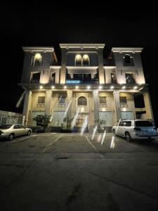 a building with cars parked in front of it at night at Rose Neri Lavender روز نيري الخزامى in Al Khobar