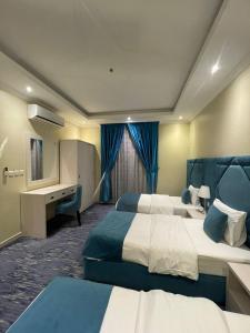 a hotel room with two beds and a desk at Rose Neri Lavender روز نيري الخزامى in Al Khobar