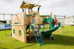 two children playing on a playground with a slide at 2 bedroom static caravan on quiet park near Caernarfon & Snowdonia in Caernarfon