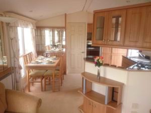 a kitchen with a table and a dining room at 2 bedroom static caravan on quiet park near Caernarfon & Snowdonia in Caernarfon