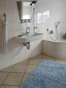 W łazience znajduje się umywalka, wanna i niebieski dywan. w obiekcie Ferienwohnung Rosenpflanzer w mieście Bad Oeynhausen