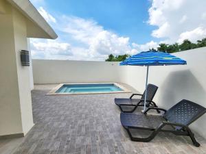 un patio con 2 sillas, una sombrilla y una piscina en Precioso apartamento en un complejo residencial con picina, en La Ciénaga