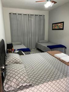1 Schlafzimmer mit 2 Betten und einem Fenster mit Vorhängen in der Unterkunft Casa 6 Suites e Eventos in Itaipuaçu