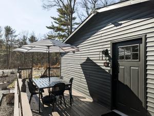 une table et des chaises avec un parasol sur une terrasse dans l'établissement Pinewood Bungalow - Luxury Cabin, Kid-Friendly, à Catskill 3 autres photos