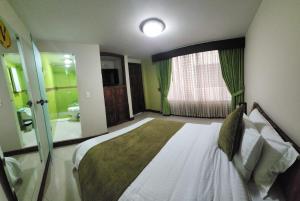 1 dormitorio con 1 cama grande y baño en Apartahotel Vincent Suites, en Pasto