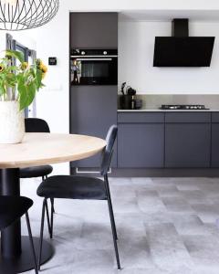 a kitchen with a wooden table and chairs and a table and a kitchen at Delightful luxury 2-bedroom holiday home in nature in Otterlo