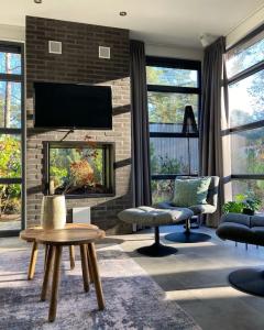 a living room with a fireplace and a tv at Delightful luxury 2-bedroom holiday home in nature in Otterlo